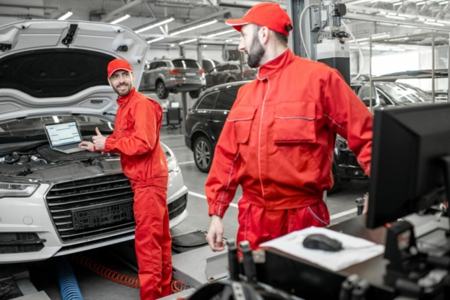 Auto mechanics doing diagnostics with laptop
