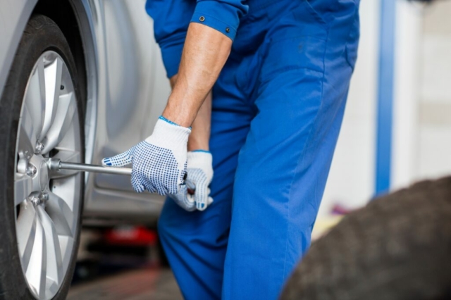 mechanic with screwdriver changing car tire