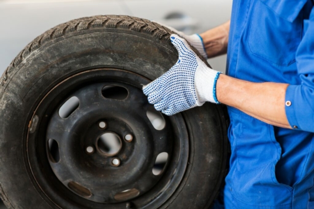 mechanic with wheel tire at car workshop